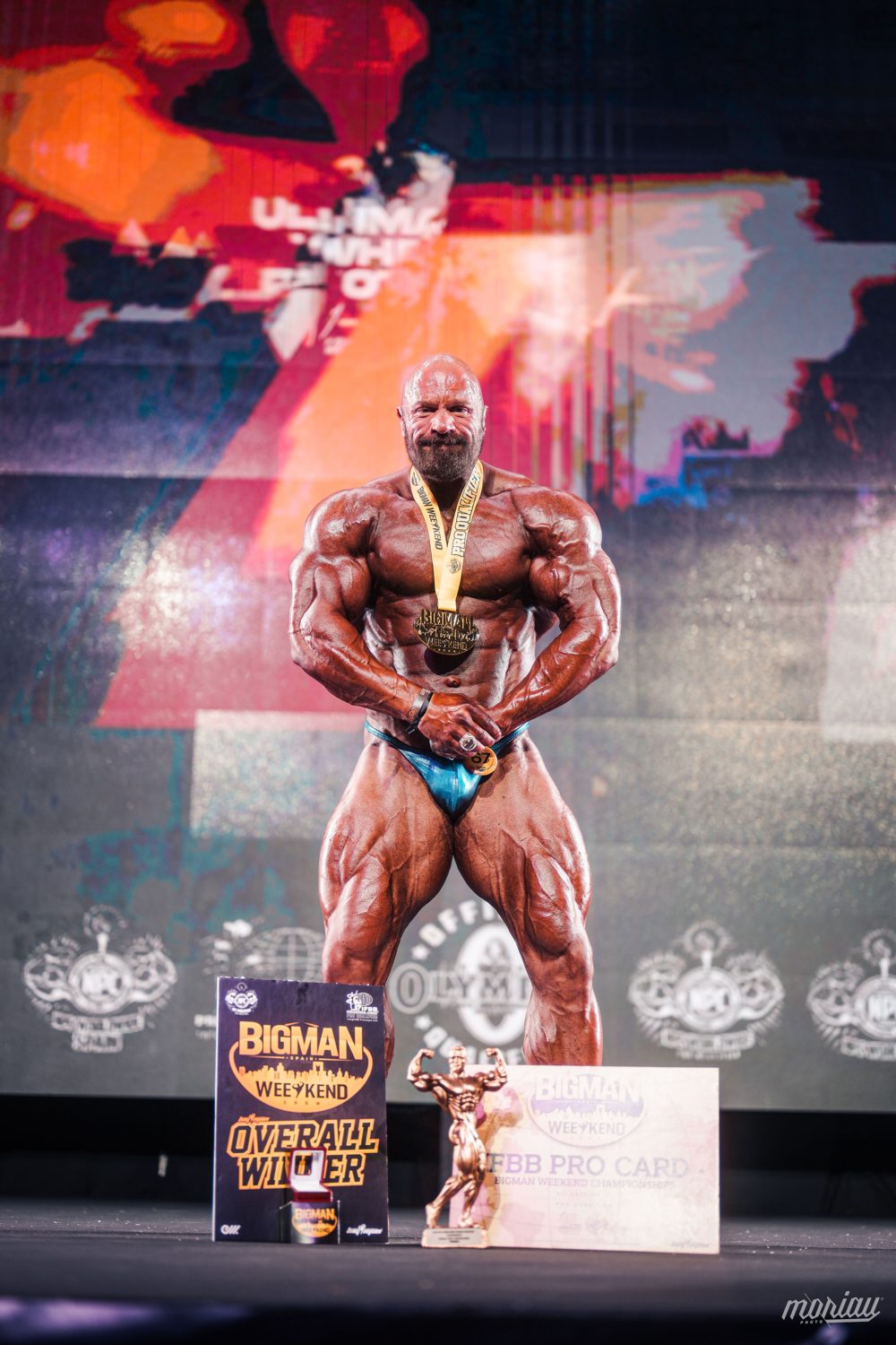 Tobias Hahne auf der Bühne mit Medaille, Overall-Siegertafel und IFBB Pro Card