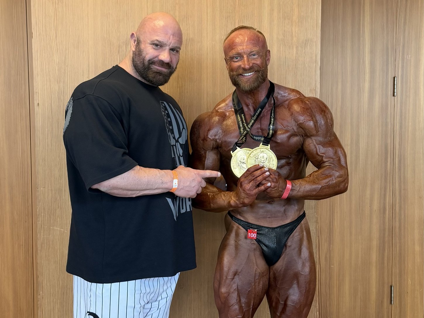 Tobias Hahne backstage mit seinem Athleten, der zwei Goldmedaillen hält